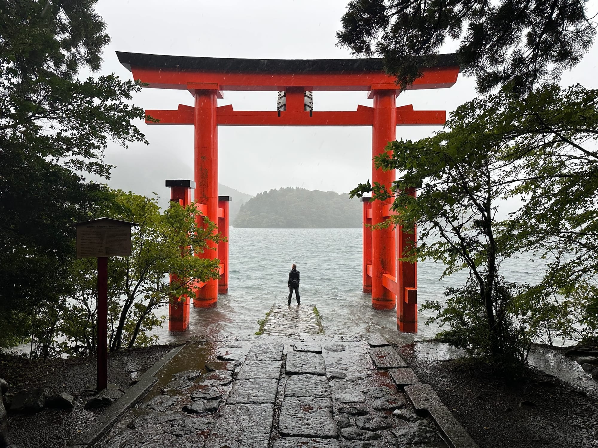 Rachel standing underneath the Heiwa-no-Torii, in the pouring rain, close to the lake. Image taken by Johann.