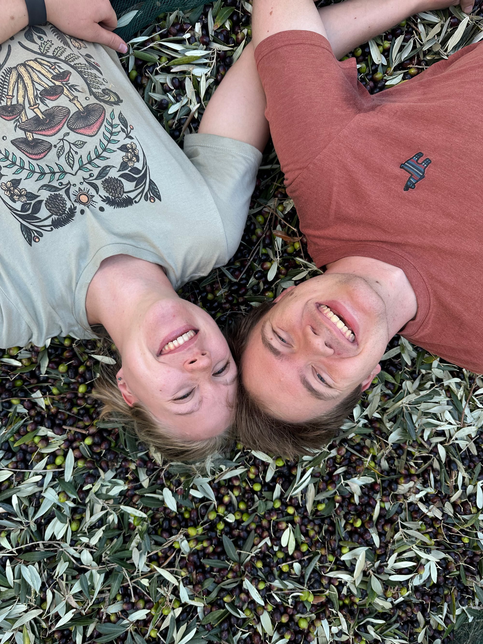 Rachel and Johann lying on a bed of olives.